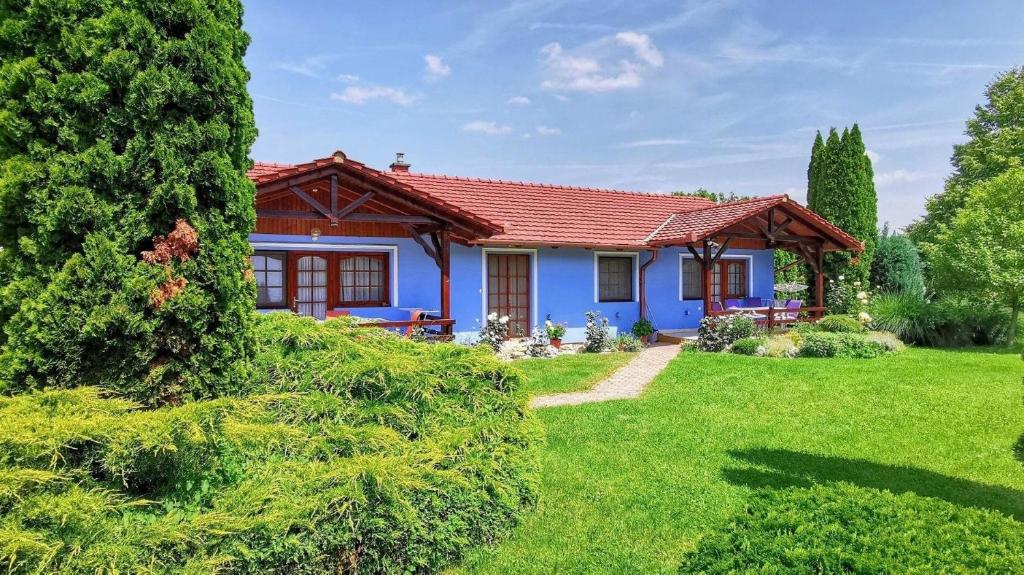 una casa azul con techo rojo en un patio en Ferienwohnung für 2 Personen 1 Kind ca 40 qm in Zalakaros, Westungarn Zala, en Zalakaros