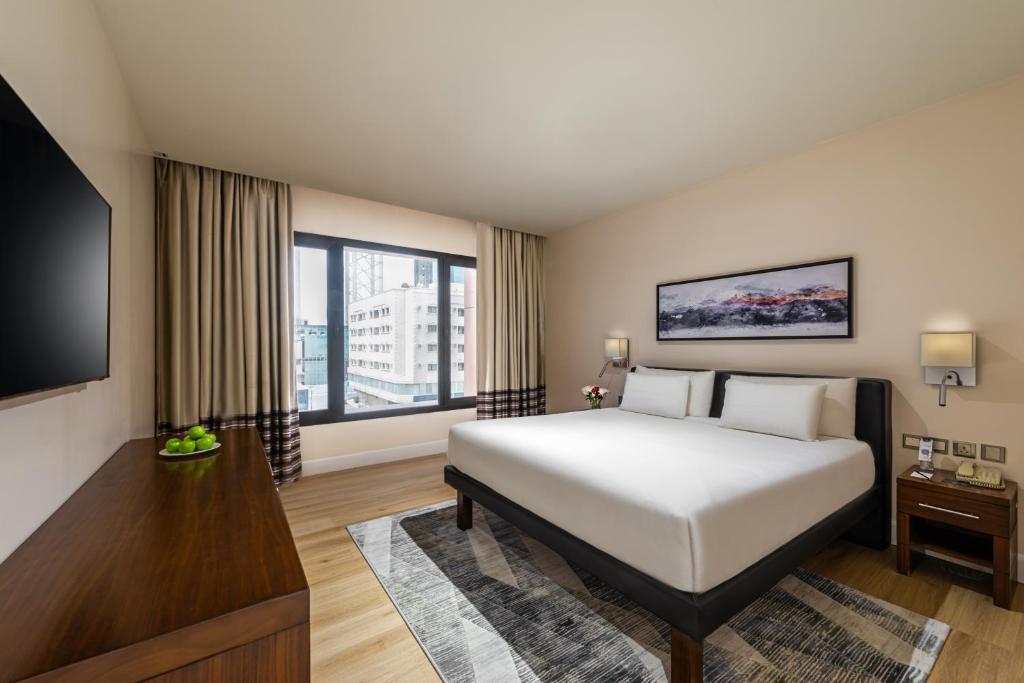 a bedroom with a large bed and a large window at Novotel Suites Riyadh Olaya in Riyadh