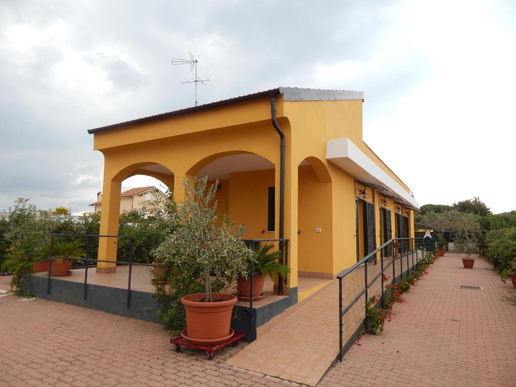 un bâtiment jaune avec une terrasse couverte ornée de plantes en pot dans l'établissement Il Melograno, à Albenga