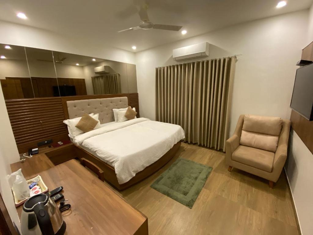 1 dormitorio con 1 cama y 1 silla en HOTEL EVERSHINE, en Rajkot