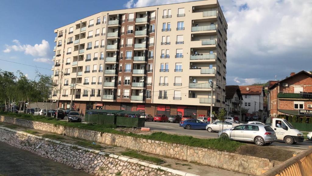 a large apartment building with cars parked in front of it at Apartman Magnolia in Novi Pazar