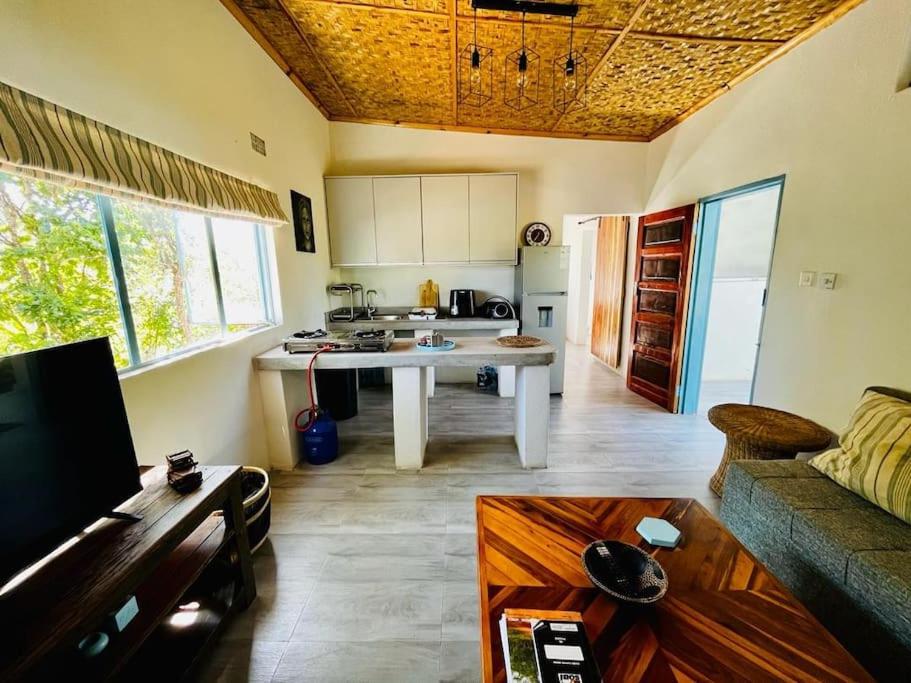 eine Küche und ein Wohnzimmer mit einem Tisch und einem Sofa in der Unterkunft Charming Cottage in the wilderness on 5 Acres in Lusaka