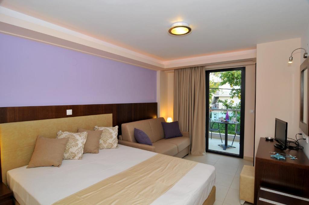 Panorama Inn Hotel في باراليا كاتيرينّيس: غرفة نوم بسرير واريكة وتلفزيون
