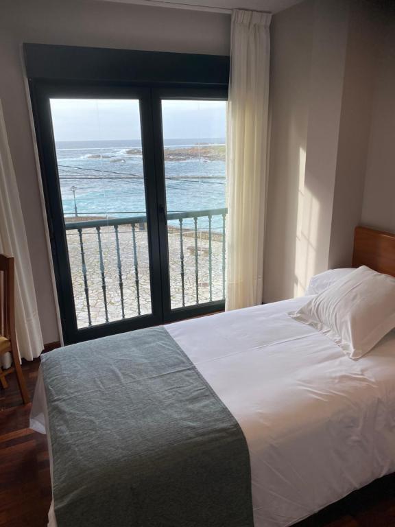 a bedroom with a bed and a view of the ocean at APARTAMENTO AUGAS DO COIDO in Muxia