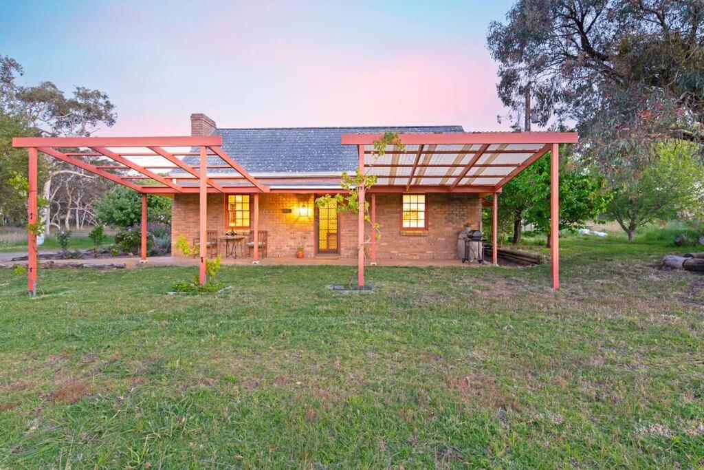 a brick house with a pergola in a yard at Blueberry Farm Cottage in Willunga