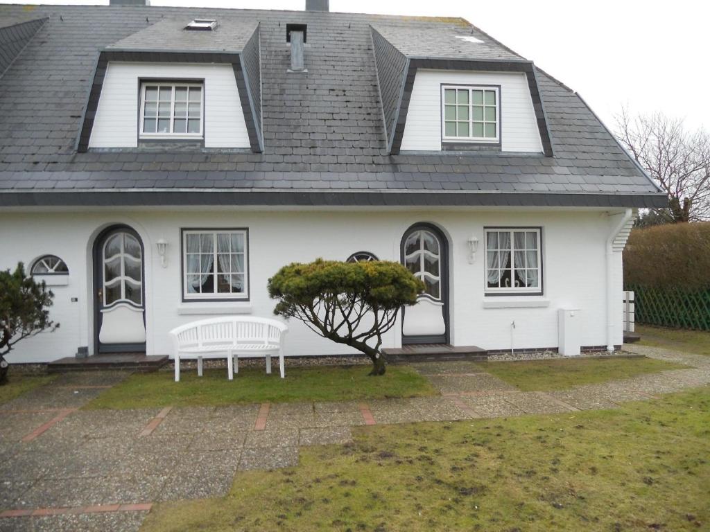 una casa blanca con un banco delante en Ferienwohnung für 2 Personen ca 55 qm in Munkmarsch, Nordfriesische Inseln Sylt - a87454, en Munkmarsch