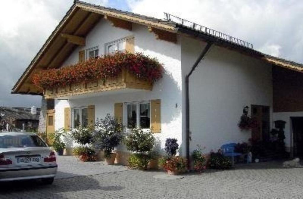 une maison blanche avec une voiture garée devant elle dans l'établissement Ferienwohnung für 5 Personen ca 80 qm in Regen, Bayern Bayerischer Wald, à Regen