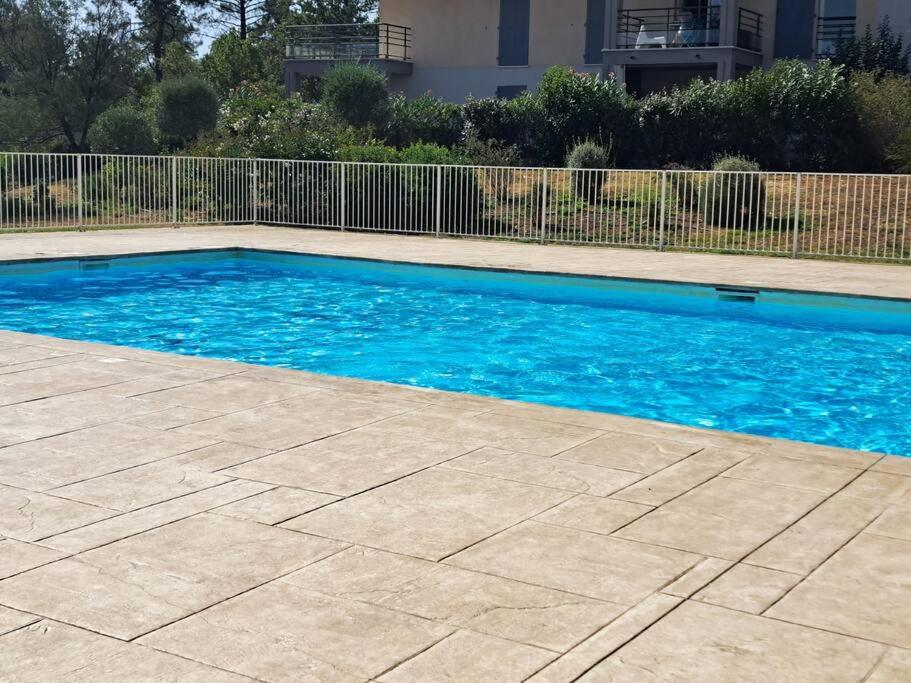 une piscine avec de l'eau bleue dans une cour dans l'établissement Magnifique T3 neuf, jardin, piscine, 5' de la mer, à Roquebrune-sur Argens