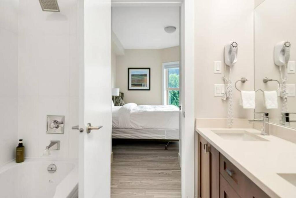 a bathroom with two sinks and a bedroom with a bed at Lakeview Majesty: Lavish 7-BR Penthouse Retreat With Rooftop Panorama in Harrison Hot Springs