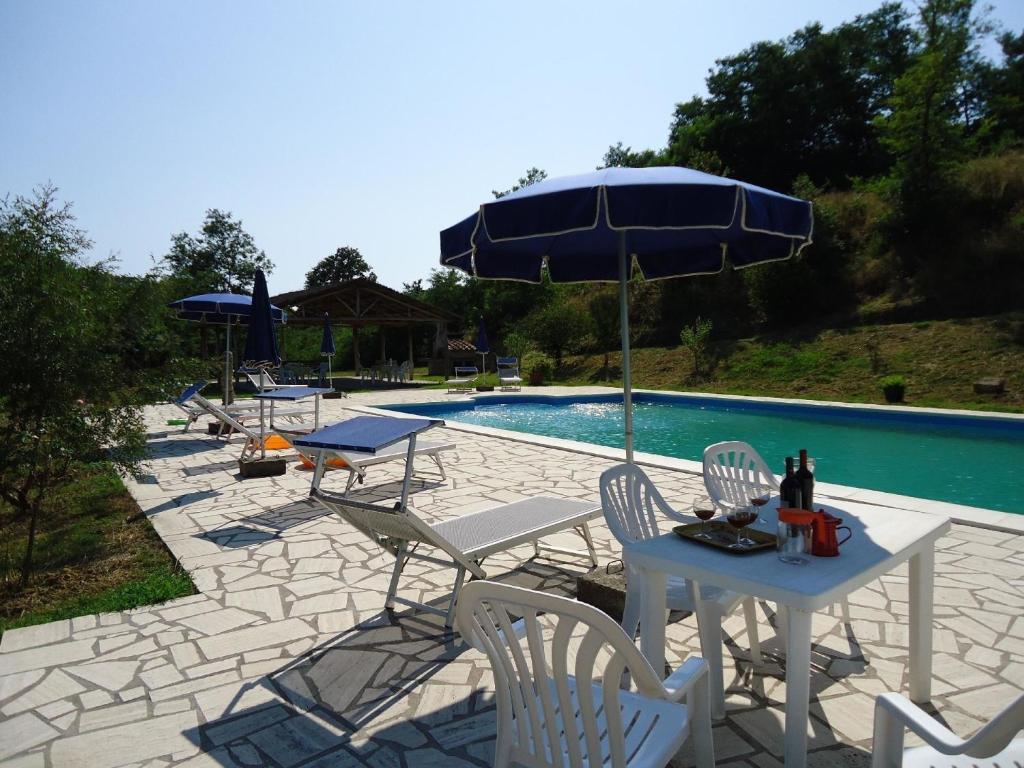 un patio con sillas y una sombrilla junto a la piscina en Ferienwohnung für 5 Personen ca 80 qm in Fauglia, Toskana Etruskische Küste, en Fauglia