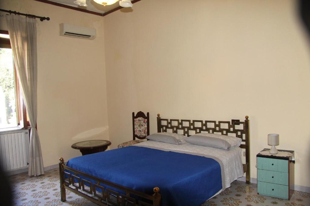 1 dormitorio con cama con sábanas azules y ventana en Casa de Rosa, en Vietri