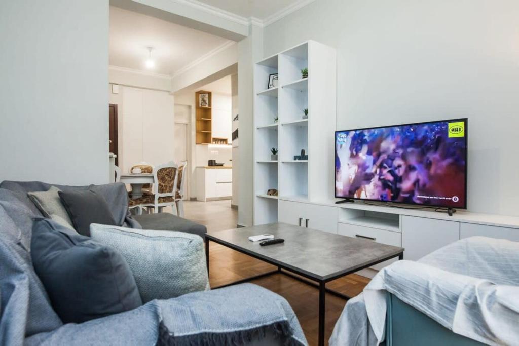 uma sala de estar com um sofá e uma televisão de ecrã plano em Brand new apt in Zografou em Atenas