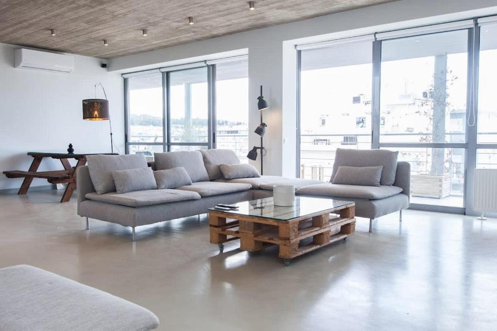 a living room with two couches and a coffee table at Penthouse with 360 View of Athens and Private Gym in Athens