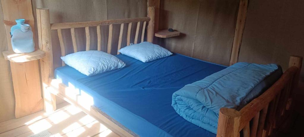 Bett mit blauer Bettwäsche und Kissen in einem Zimmer in der Unterkunft Cabanes des Landes- cabane sur pilotis in Saint-Éloy-les-Tuileries