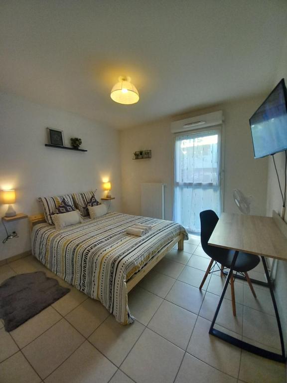 - une chambre avec un lit, une table et un bureau dans l'établissement Cocon reposant à 10min du centre de Bordeaux, à Lormont