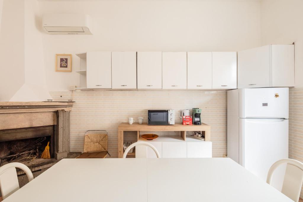 a kitchen with white cabinets and a table and a fireplace at Casa Brando in Santa Maria delle Mole