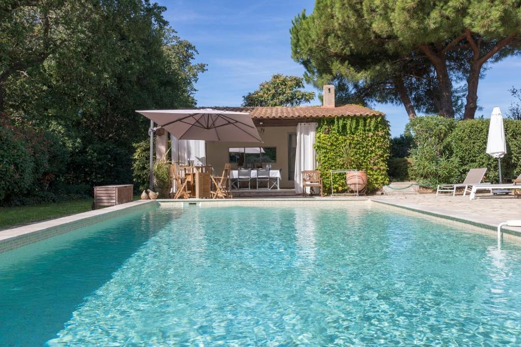 - une piscine avec un parasol et une maison dans l'établissement La Bastide du Bouchou, à Six-Fours-les-Plages