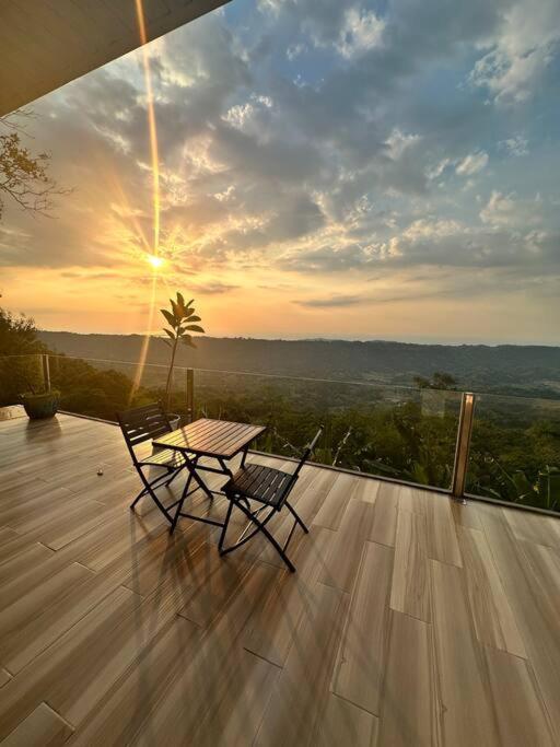 - une table et des chaises sur une terrasse avec vue sur le coucher du soleil dans l'établissement Veronica Guesthouse w/ Breathtaking Mountain View, à Bagolig