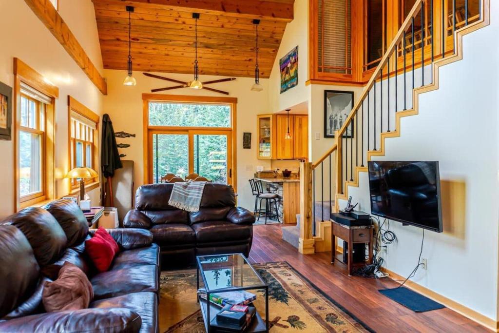 a living room with a leather couch and a tv at Tranquil 3BR Home Access To Trails and Mtn Views in Blue River