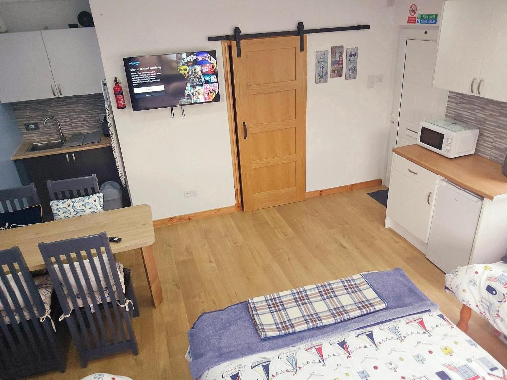 a room with a kitchen and a table and a door at Four Winds Holiday Let in Nairn