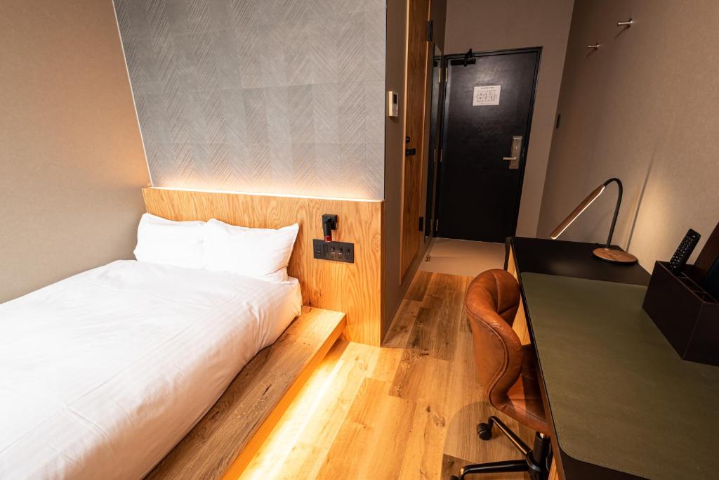 ein kleines Schlafzimmer mit einem Bett und einem Schreibtisch in der Unterkunft ArC LIFESTYLE SPACE & HOTEL in Mito