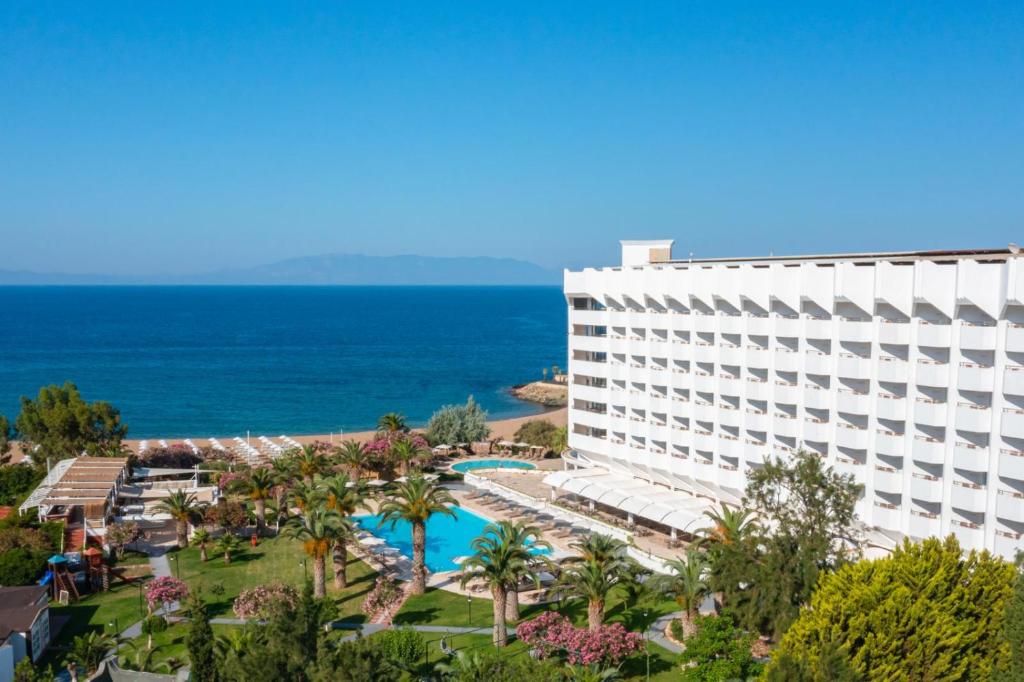 a hotel with a pool and the ocean in the background at Club Beyy Resort Hotel - Ultra All Inclusive in İzmir