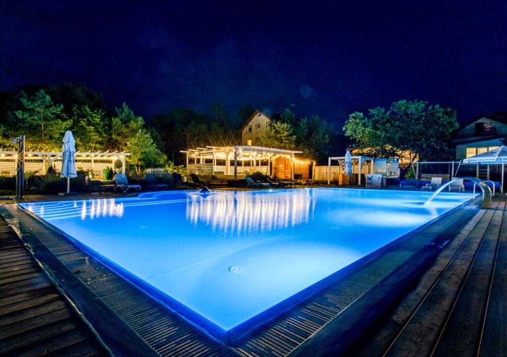 uma grande piscina azul à noite em OŚRODEK KOLONIJNO WCZASOWY MEWA - przy plaży z basenem z podgrzewaną wodą i mini SPA em Niechorze