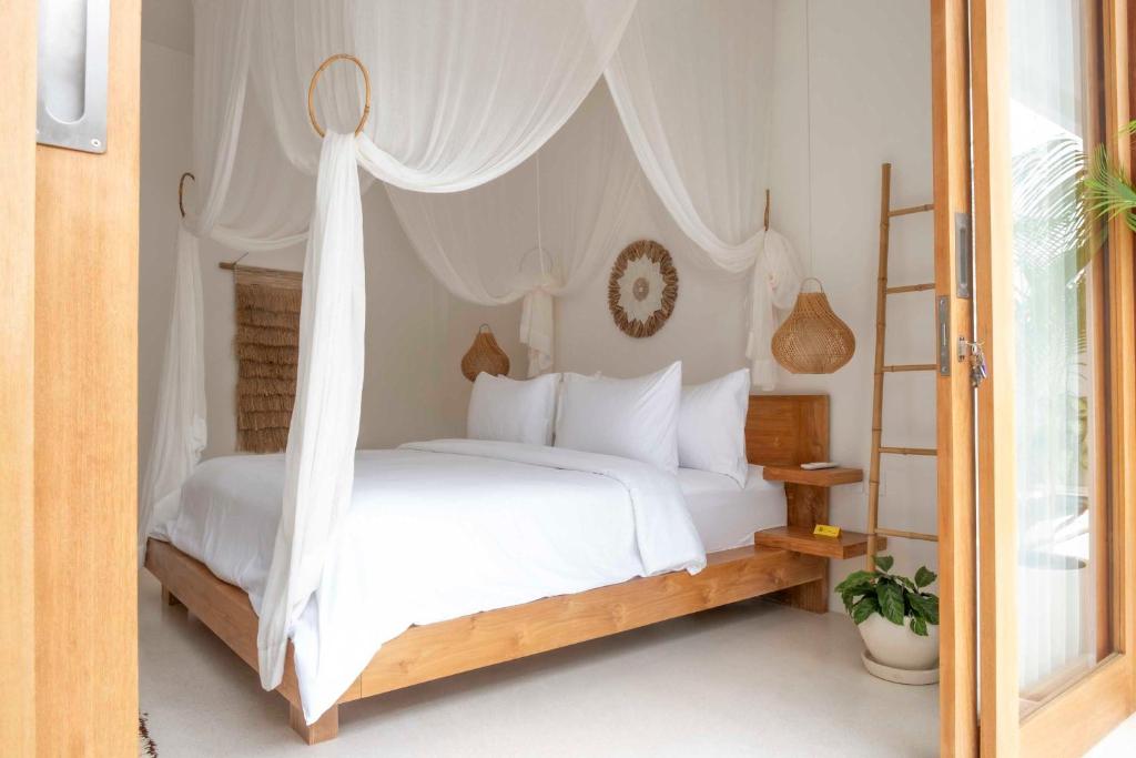 um quarto com uma cama de dossel branca em ARTI by Umah - Pererenan em Canggu