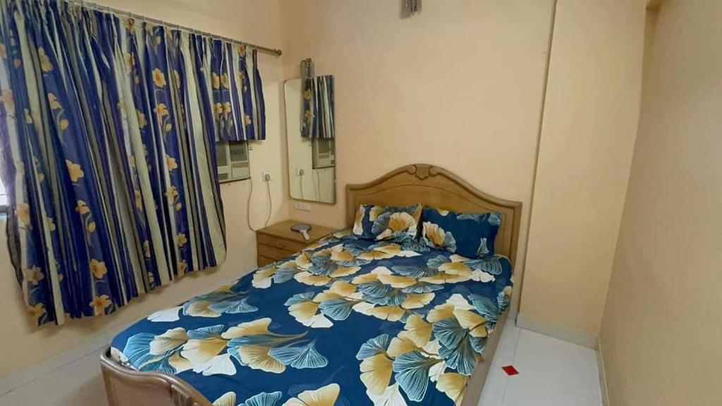 a bedroom with a bed with a blue and yellow blanket at F2 apartments in Mumbai