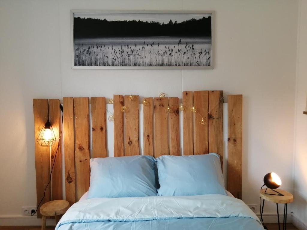 Bett mit einem Kopfteil aus Holz in einem Schlafzimmer in der Unterkunft Villa Atlantis 4-8 pers super équipée proche océan in Soustons