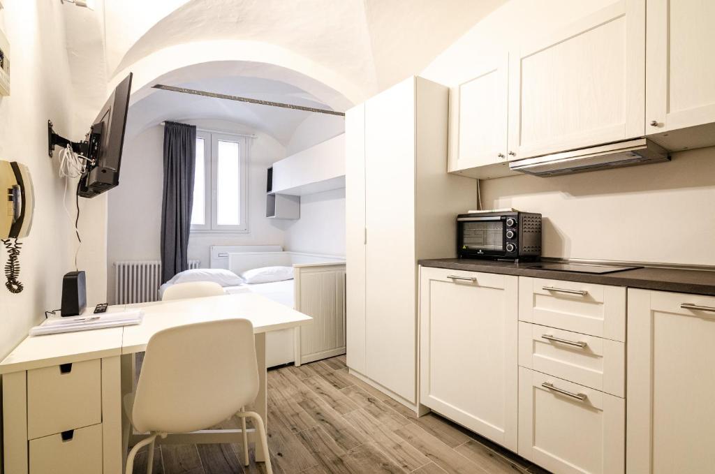 a kitchen with white cabinets and a table with a microwave at Nosadella Studio in Bologna