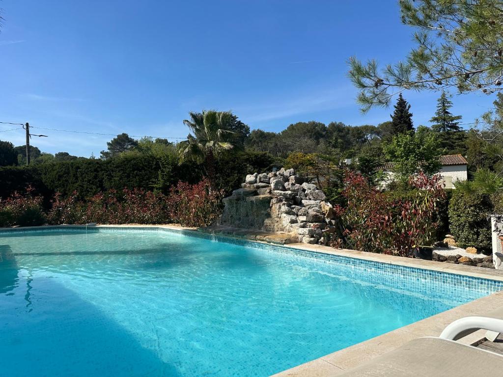 a swimming pool with a waterfall in a yard at Central Valbonne Villa in Valbonne
