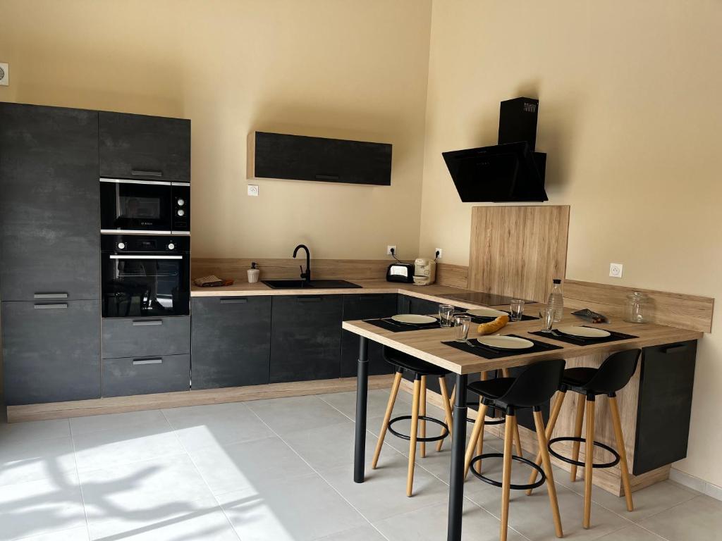 een keuken met zwarte kasten en een eiland met barkrukken bij Le capèu in Mollégès