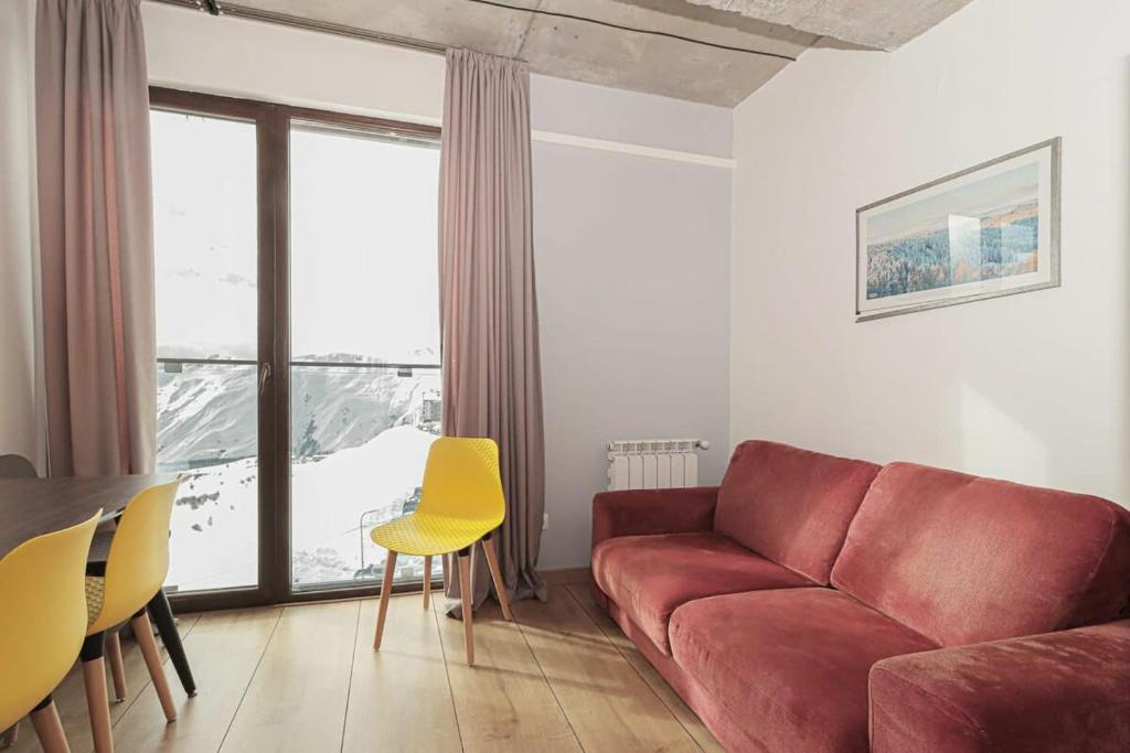 a living room with a red couch and a table at Cozy Studio Apartment For 4 in New Gudauri in Gudauri