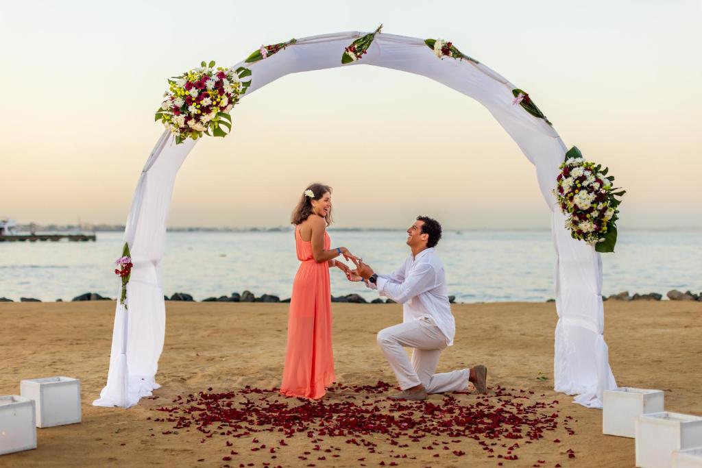 a bride and groom dancing under an arch on the beach at Desert Rose Resort in Hurghada
