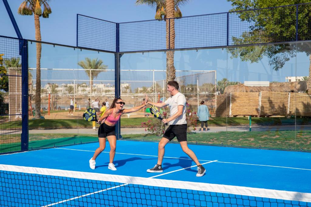 a man and woman shaking hands on a tennis court at Desert Rose Resort in Hurghada