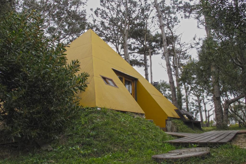 uma casa amarela sentada no topo de uma colina em Piramide em Punta Del Diablo