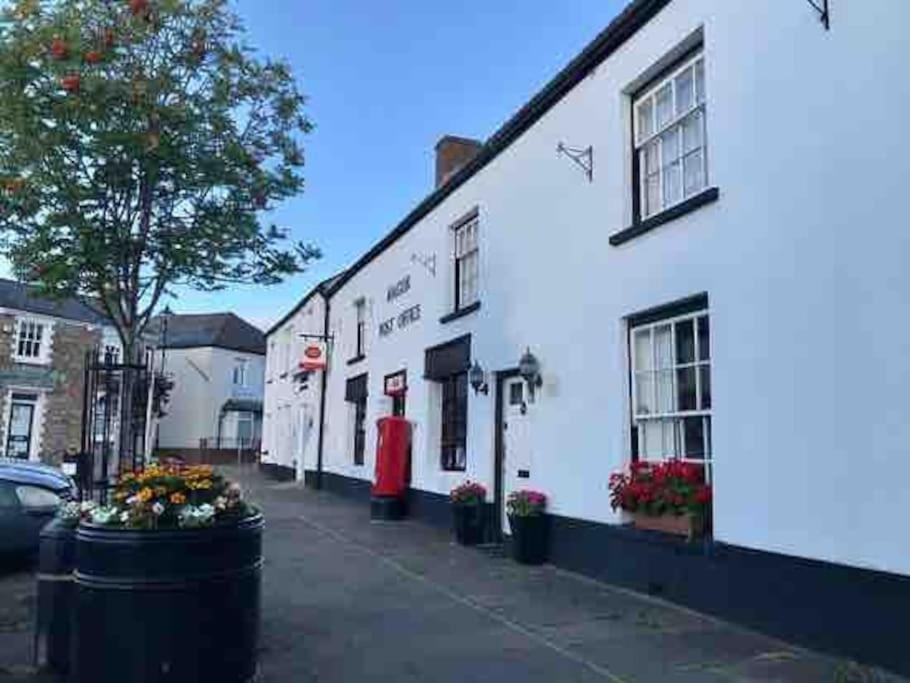 um edifício branco com uma porta vermelha numa rua em Spacious Stylish House Close to M4 Private Parking em Magor