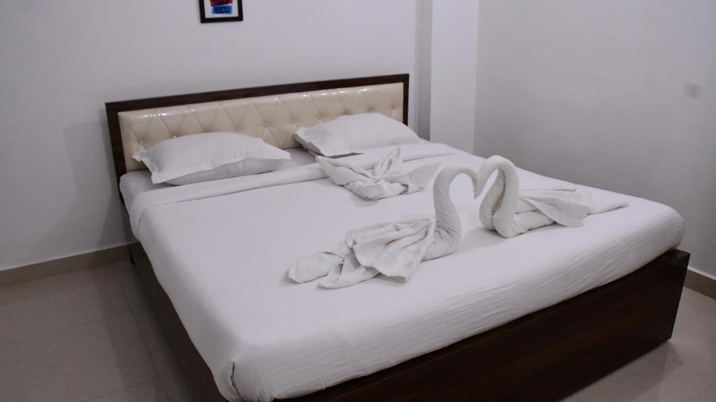 ein Bett mit weißer Bettwäsche und Handtüchern darauf in der Unterkunft Rivasa homes in Deoghar