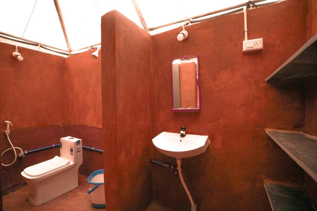 a bathroom with a white sink and a toilet at Glampi In Hampi in Hampi