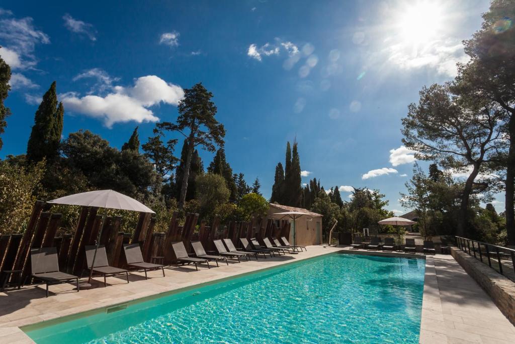 uma piscina com cadeiras e guarda-sóis e o sol em Les Cabanes Dans Les Bois Logis Hôtel em Villedubert