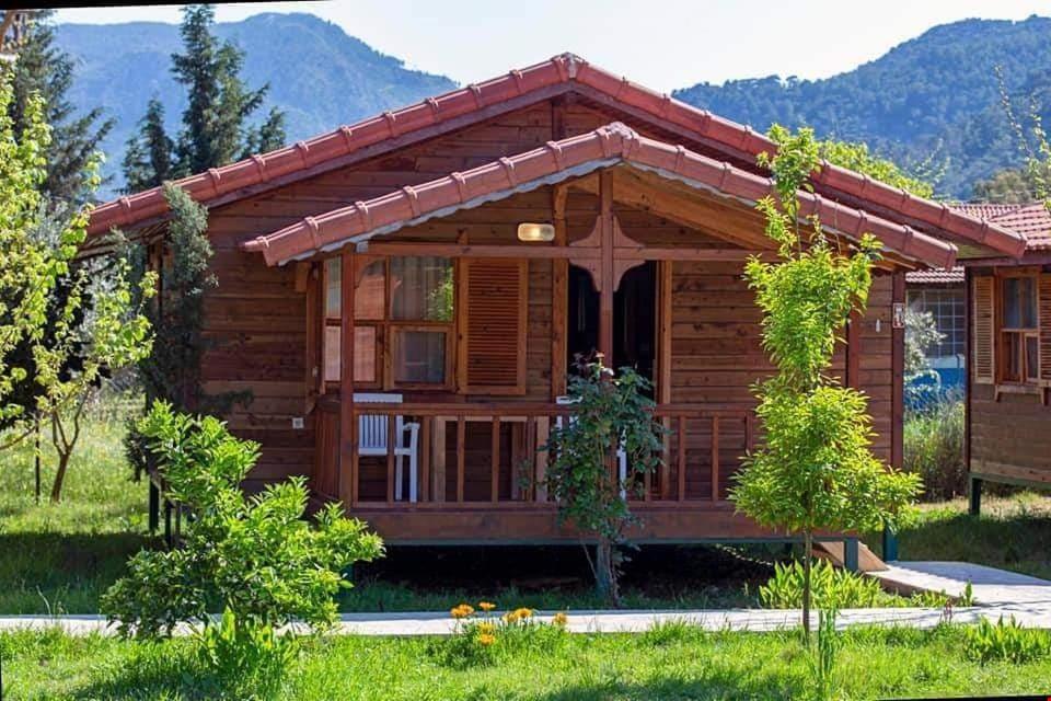 a log cabin with mountains in the background at Cirali La Maison Hotel in Kemer