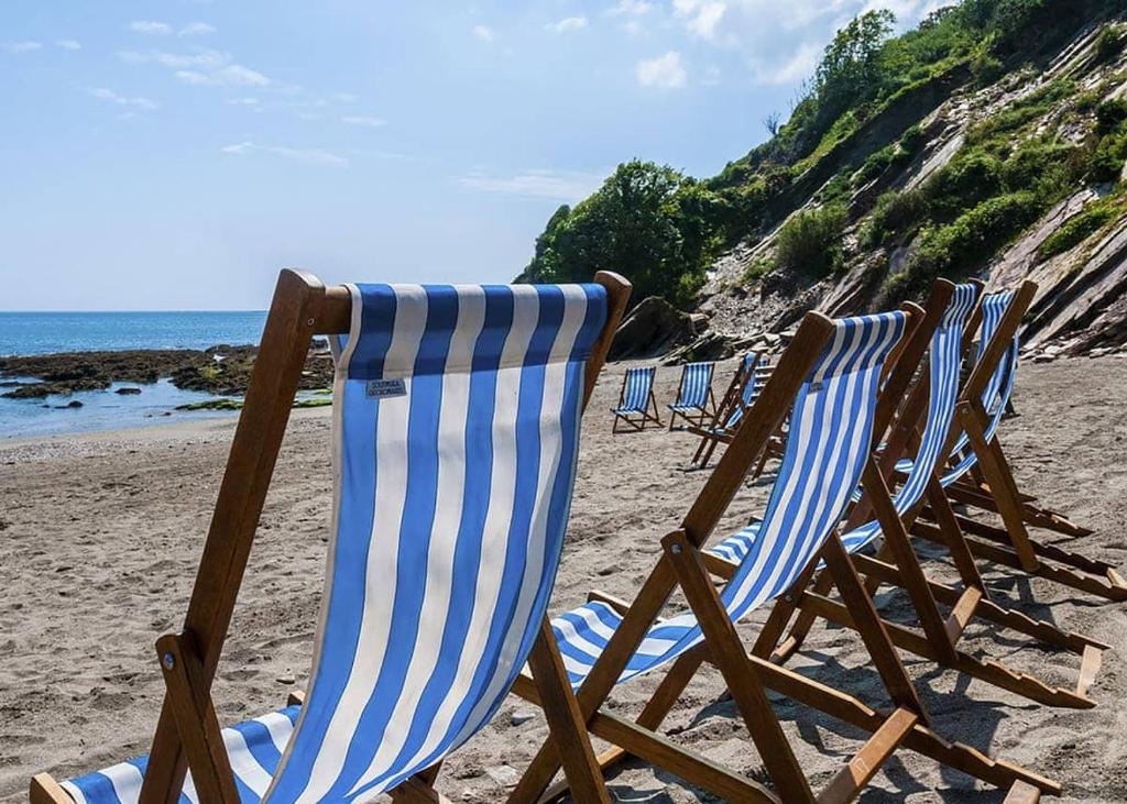 eine Reihe von Liegestühlen am Strand in der Unterkunft Millendreath Beach Resort in Looe