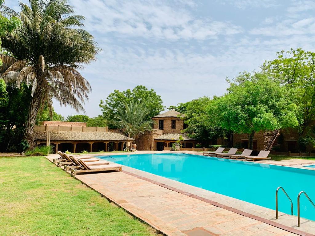 Dechu的住宿－Manvār Shergarh , The Desert Resort，一个带躺椅的游泳池以及一座房子