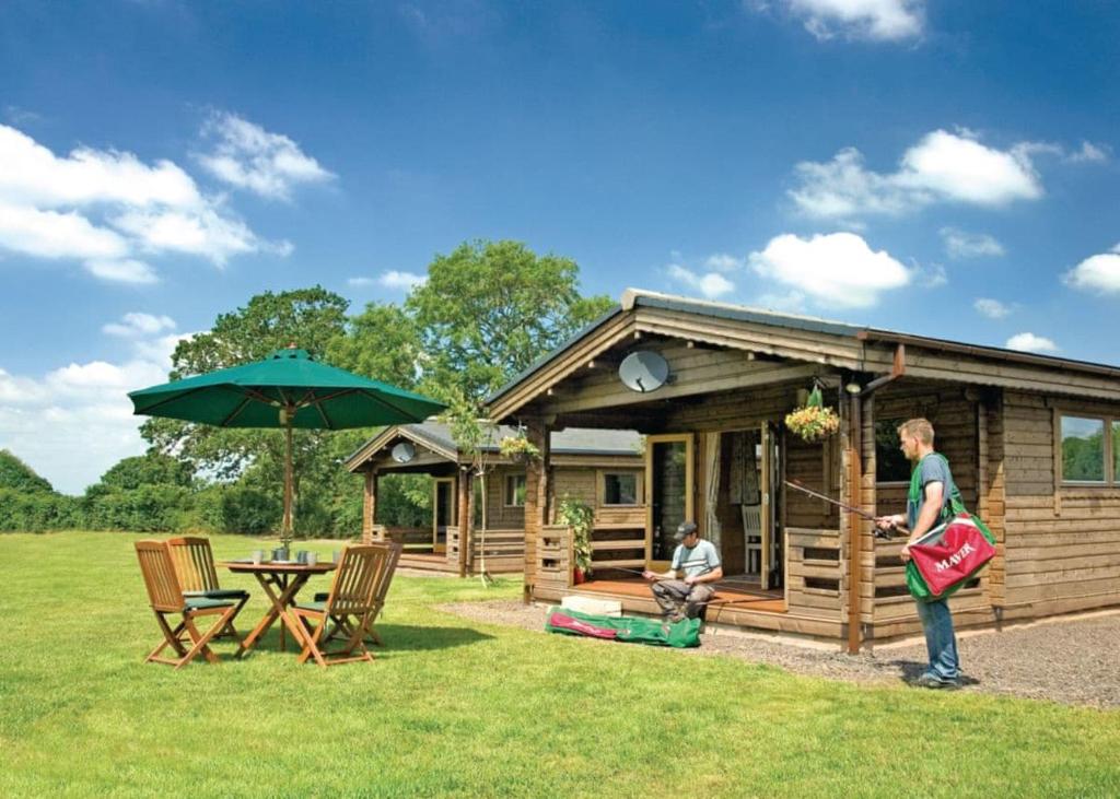 a man standing in front of a cabin at Goodiford Mill Lakes in Kentisbeare