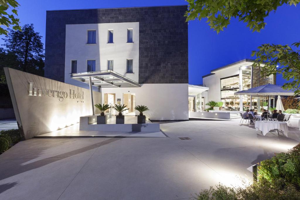 a large white building with tables and chairs in front of it at Inverigo Hotel in Inverigo