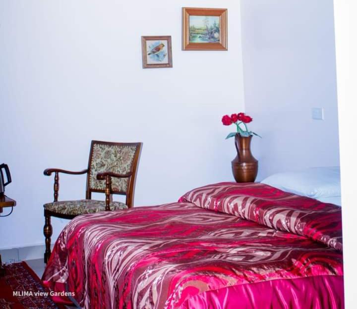 1 dormitorio con 1 cama, 1 silla y 1 jarrón con flores en MLIMAVIEW GARDENS BY Cradle Ranch, en Nanyuki
