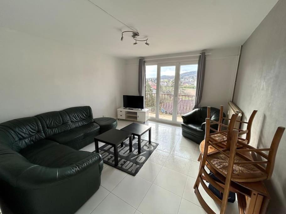 een woonkamer met een zwarte leren bank en stoelen bij Spacieux appartement avec balcon in Belfort