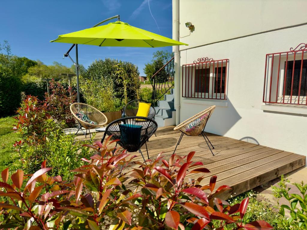 una terraza de madera con sillas y una sombrilla amarilla en Maison des Chênes 64, en Boucau
