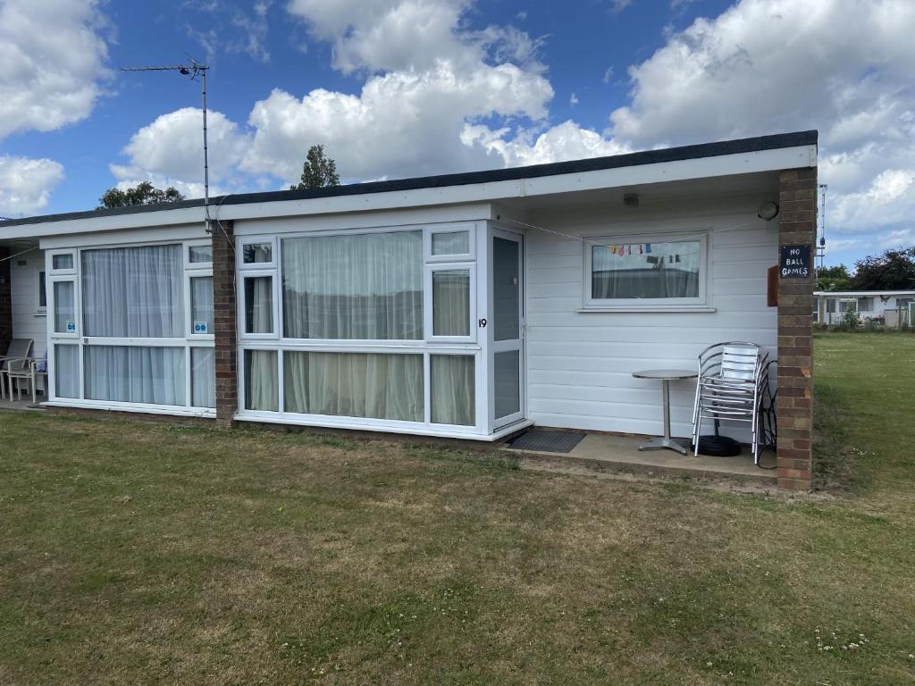 a mobile home with a table and chairs in a yard at Bermuda Chalet - Hemsby in Hemsby